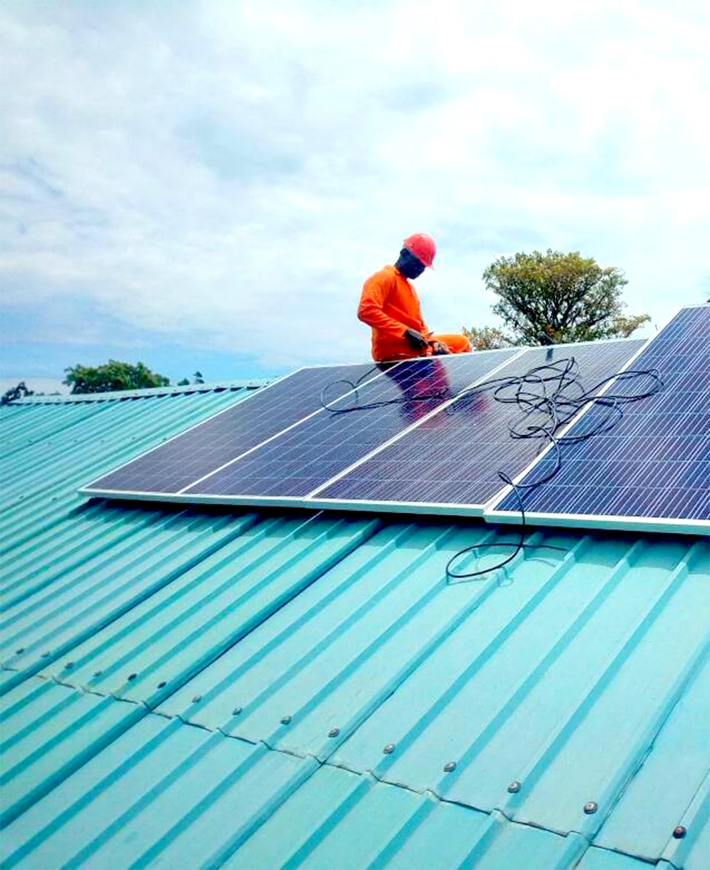 Installation av solpaneler på ett tak i Uganda